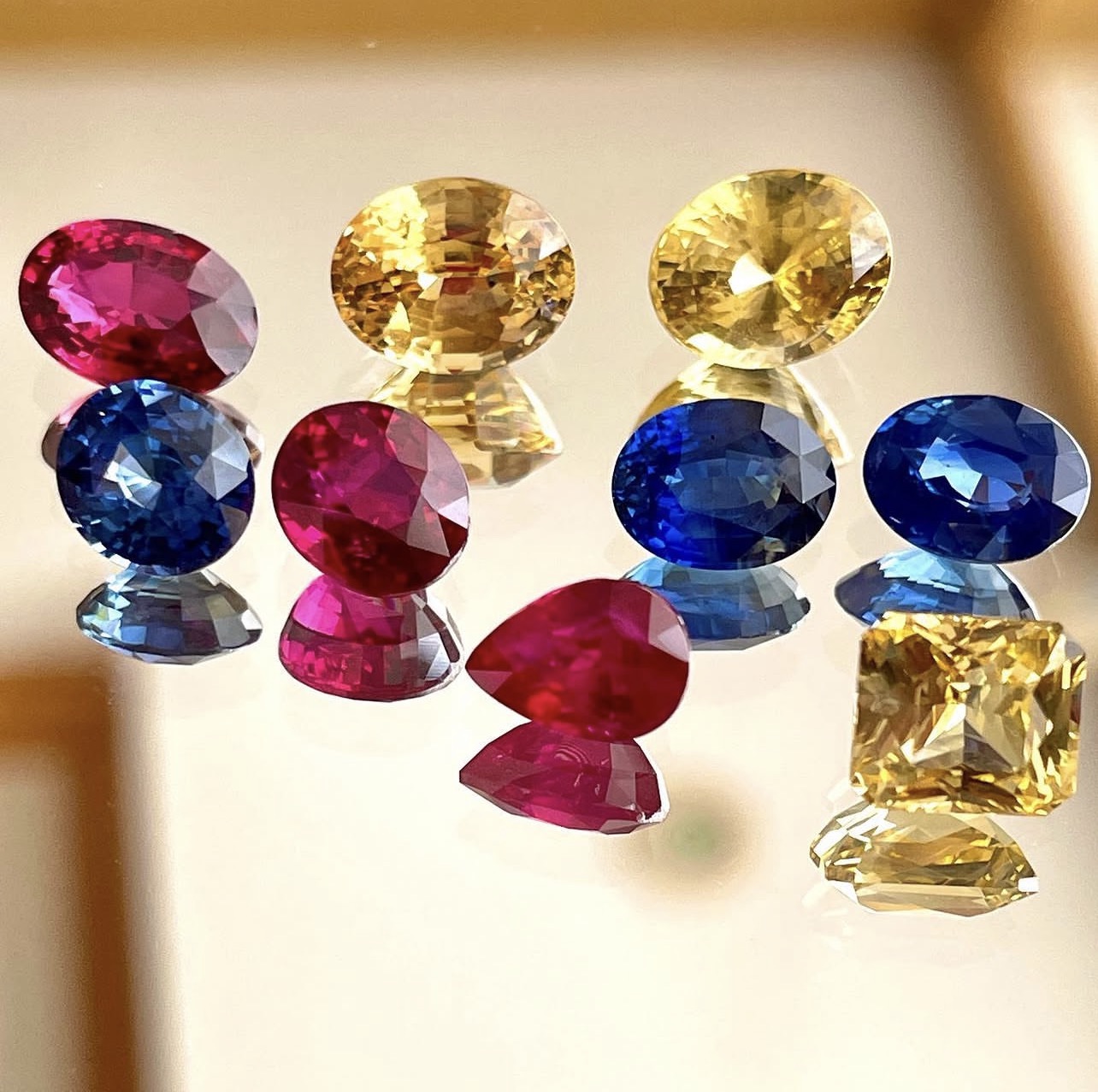 Rubies, blue sapphires and yellow sapphires on a mirror